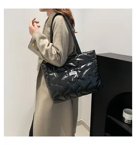 Detailed side view of a model carrying a large black quilted puffer fabric tote bag
