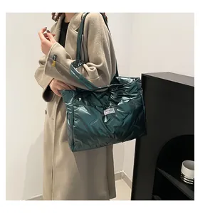Close-up of a stylish metallic green quilted down tote bag carried over the shoulder
