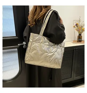 Detailed macro view of stylish silver quilted puffer tote bag carried on woman's shoulder