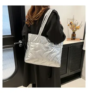 Large silver metallic quilted puffer tote bag shown styled on shoulder in lifestyle setting