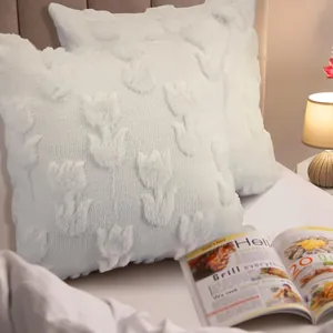 Close-up of white plush embroidered throw pillow cases with textured tulip floral patterns.