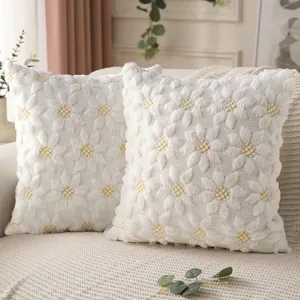 Close-up of white shaggy throw pillow covers with yellow quilted daisy floral pattern.