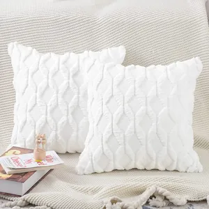 Close-up detail of two white plush quilted throw pillow covers on a cozy knitted sofa