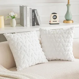 Detail showing the plush texture and embroidered heart patterns on a white cushion cover