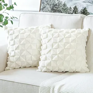 Close-up view of elegant white plush quilted throw pillow covers on a beige sofa