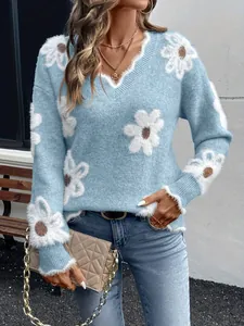 Dettaglio del maglione in maglia azzurro con scollo a V e grandi motivi floreali bianchi.