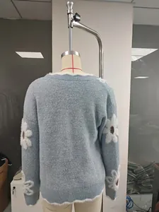 Vista posteriore di un maglione lavorato a maglia blu chiaro con fiori sulle maniche