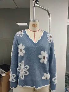 Vista dettagliata di un maglione in maglia blu con scollo a V e motivi floreali eleganti