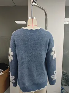 Vista posteriore dettagliata di un maglione blu con applicazioni floreali bianche in 3D