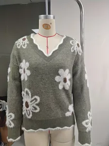 Vista dettagliata di un elegante maglione verde con scollo a V e jacquard floreale bianco.