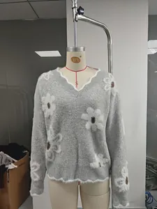 Dettaglio di un maglione grigio a maglia con scollo a V e fiori bianchi a rilievo