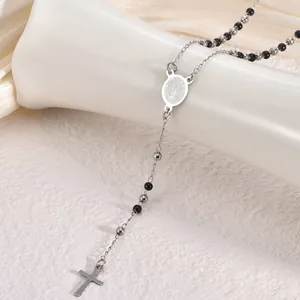 Detail macro shot of stainless steel rosary necklace with black beads and silver cross