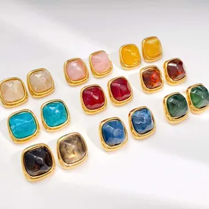 Close-up of colorful square resin stud earrings with gold stainless steel frames.