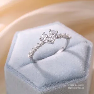 Detail view of a sparkling S925 silver ring with heart zircon and pearls on a blue box.