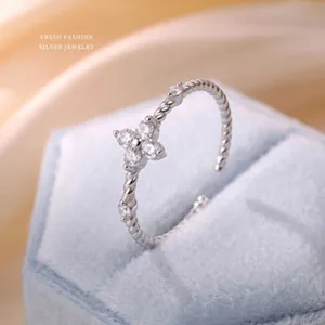 Macro detail of a silver flower ring with clear zircons on a light blue velvet jewelry box.