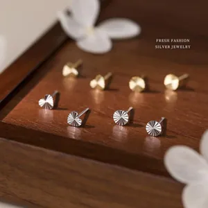 Macro view of dainty s925 silver heart and round stud earrings on a wooden display stand