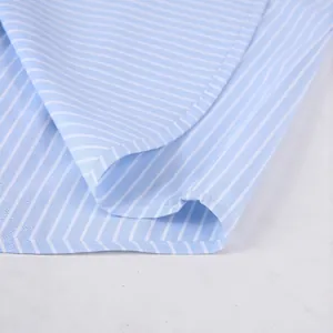 Primo piano dell'orlo di una camicia da uomo a righe blu e bianche, dettaglio tessuto