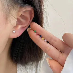 Close-up van verschillende kleuren mini-zirkonia-oorknopjes op een vinger geplaatst