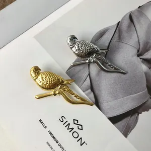 Detailed macro shot of gold and silver parrot brooches on a textured background.