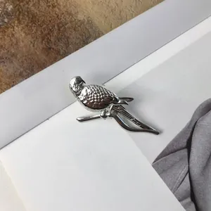 Detailed macro view of a silver parrot perched on a branch brooch pin for suits