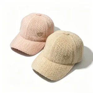 Close-up detail of soft fuzzy winter baseball caps in pink and beige with heart