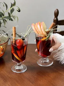 Elegant glass goblet for mulled wine with fresh fruit and cinnamon stick garnishes