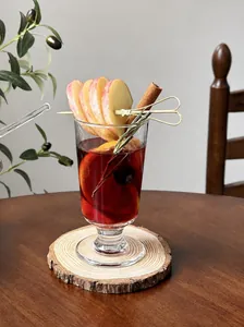 Detailed view of a festive hot mulled wine glass with fresh apple slices and rosemary