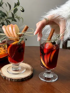 Elegant mulled wine glasses filled with red wine, apple slices, and cinnamon sticks detail