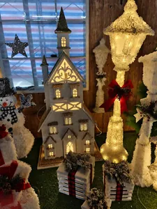 Close-up of illuminated white Christmas church building with festive snowman and lamp posts