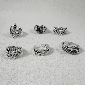 Variété de bagues punk gothiques avec motifs tête de mort et étoile sur fond texturé.