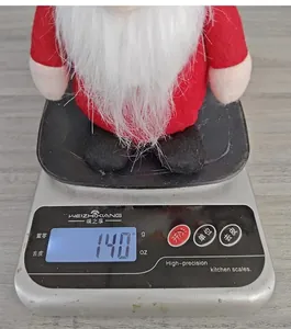 Detail view of the Christmas plush gnome doll placed on a scale weighing 140 grams