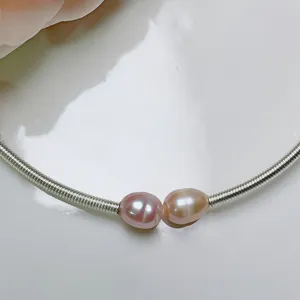 Close-up detail of lavender freshwater pearls on a silver-toned coiled wire bracelet.