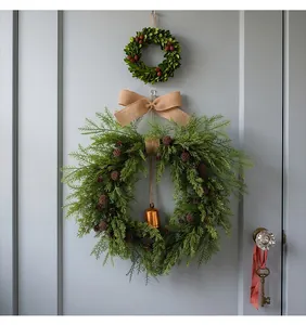 Rustic Christmas cedar wreath with pine cones and a burlap bow hanging on a gray door