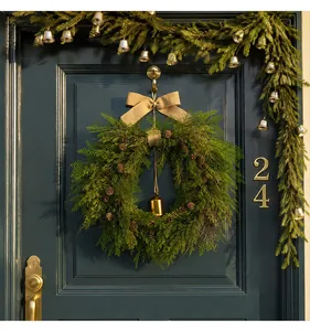Close-up of Christmas wreath with pine cones and golden bell on a dark blue door