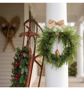 Detail view of a rustic Christmas wreath with a brass bell and pinecones on a porch