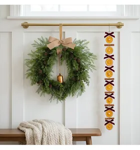 Christmas wreath with pine cones and bells next to a festive dried orange garland
