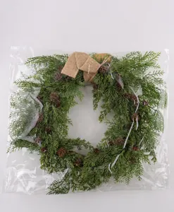Christmas pinecone wreath with burlap bow shown in clear protective plastic packaging bag