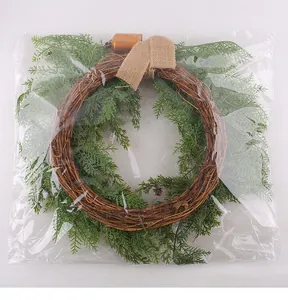 Close-up view of a Christmas cedar wreath with burlap bow and bell in plastic packaging