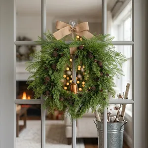 Rustic Christmas pinecone and bell wreath with a burlap bow hanging on a glass door