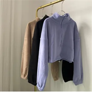 Detail view of fleece zip-up sweatshirts in tan, black, and blue colors hanging on a rack