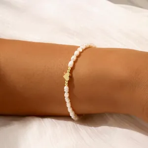 Elegant handmade irregular freshwater pearl bracelet with a dainty golden heart charm.
