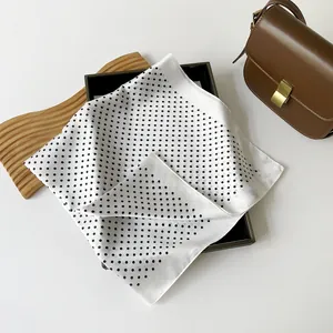 Primo piano di un foulard quadrato bianco a pois neri in stile francese su un vassoio