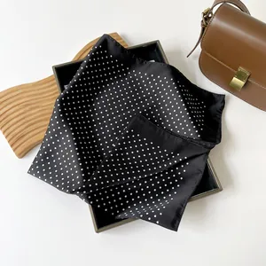 Dettaglio di un foulard quadrato nero effetto seta con pois bianchi