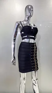 Detail view of black two-piece set with gold metal buckle accents on the skirt.