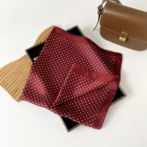 Dettaglio di un foulard quadrato in seta sintetica bordeaux a pois bianchi classici