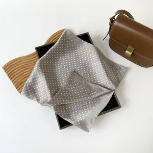 Primo piano di un foulard di seta taupe a pois bianchi per uno styling di moda