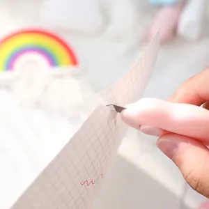 Detail view of a pink mini cloud utility knife cutting through grid paper