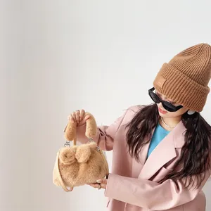 Braune Plüschhandtasche aus Kunstpelz mit dekorativer Schleife bei einem Model