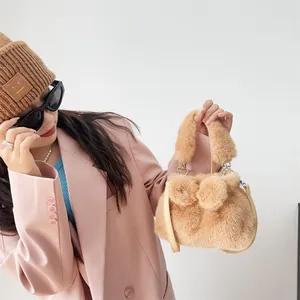 Detaillierte Ansicht einer braunen Handtasche aus Kunstpelz mit Pompons und Lederriemen.