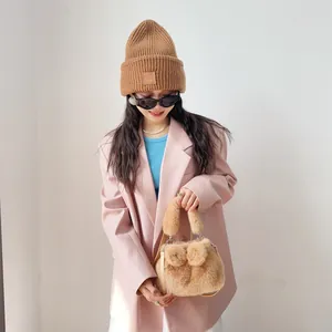 Detailansicht einer flauschigen Handtasche aus Kunstnerz mit Schleifen, gehalten von Model.